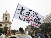 Doctors and citizens hold placards and shout slogans while marching with burning torches during a protest against the rape and murder of a P...