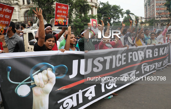 Doctors and citizens hold placards and shout slogans while marching with burning torches during a protest against the rape and murder of a P...