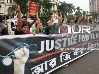 Doctors and citizens hold placards and shout slogans while marching with burning torches during a protest against the rape and murder of a P...