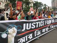 Doctors and citizens hold placards and shout slogans while marching with burning torches during a protest against the rape and murder of a P...