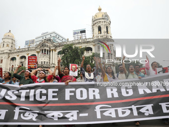 Doctors and citizens hold placards and shout slogans while marching with burning torches during a protest against the rape and murder of a P...