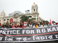 Doctors and citizens hold placards and shout slogans while marching with burning torches during a protest against the rape and murder of a P...