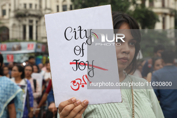 Doctors and citizens hold placards and shout slogans while marching with burning torches during a protest against the rape and murder of a P...