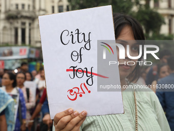 Doctors and citizens hold placards and shout slogans while marching with burning torches during a protest against the rape and murder of a P...