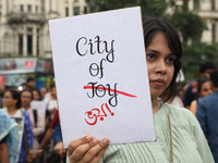 Doctors and citizens hold placards and shout slogans while marching with burning torches during a protest against the rape and murder of a P...