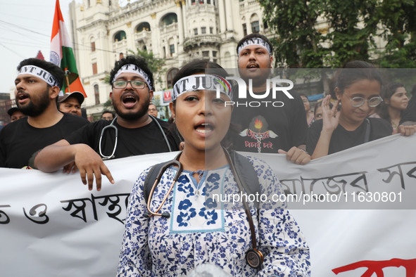 Doctors and citizens hold placards and shout slogans while marching with burning torches during a protest against the rape and murder of a P...