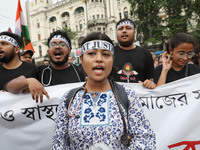 Doctors and citizens hold placards and shout slogans while marching with burning torches during a protest against the rape and murder of a P...