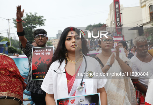 A woman dresses as a doctor and Hindu goddess Durga while doctors and citizens hold placards and shout slogans during a protest march with b...