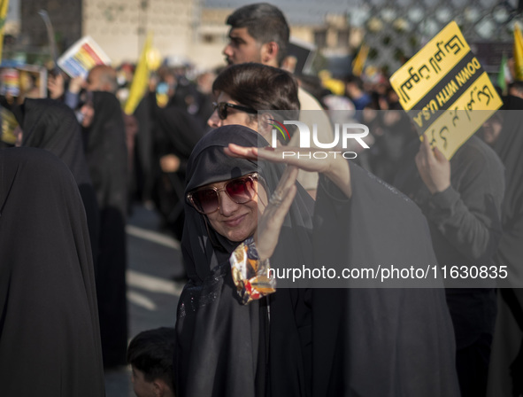 A veiled Iranian woman demonstrates a T-hand gesture used by Lebanon's Hezbollah Secretary General Hassan Nasrallah, who was killed in an Is...