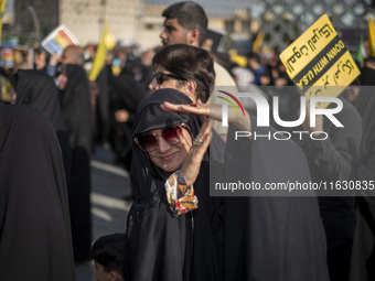 A veiled Iranian woman demonstrates a T-hand gesture used by Lebanon's Hezbollah Secretary General Hassan Nasrallah, who was killed in an Is...