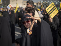 A veiled Iranian woman demonstrates a T-hand gesture used by Lebanon's Hezbollah Secretary General Hassan Nasrallah, who was killed in an Is...