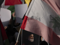 A veiled Iranian woman holds a portrait of Lebanon's Hezbollah Secretary General Hassan Nasrallah under a Lebanese flag during a gathering m...