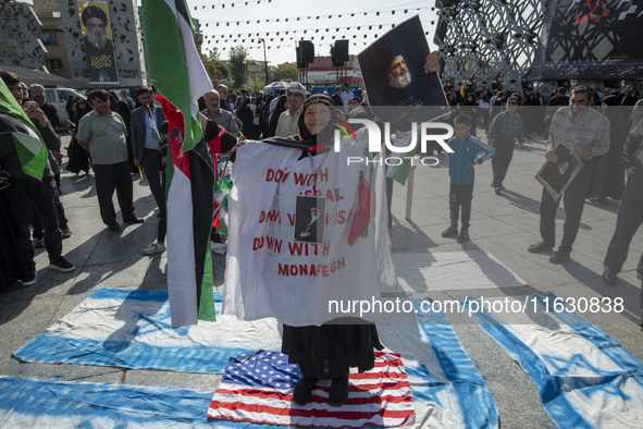 An Iranian woman wears a portrait of Iran's Supreme Leader, Ayatollah Ali Khamenei, and holds a portrait of Lebanon's Hezbollah Secretary Ge...