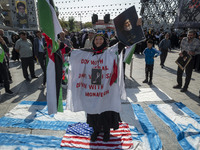 An Iranian woman wears a portrait of Iran's Supreme Leader, Ayatollah Ali Khamenei, and holds a portrait of Lebanon's Hezbollah Secretary Ge...