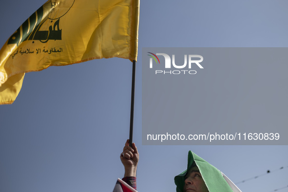 An Iranian man waves a flag of Lebanon's Hezbollah while taking part in a gathering marking the memory of Hassan Nasrallah and an Iranian co...