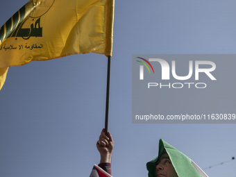 An Iranian man waves a flag of Lebanon's Hezbollah while taking part in a gathering marking the memory of Hassan Nasrallah and an Iranian co...