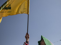 An Iranian man waves a flag of Lebanon's Hezbollah while taking part in a gathering marking the memory of Hassan Nasrallah and an Iranian co...