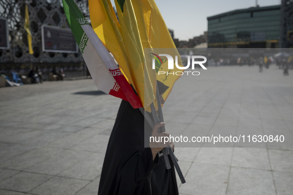 A veiled Iranian woman carries an Iranian flag and flags of Lebanon's Hezbollah before a gathering marking the memory of Hezbollah Secretary...