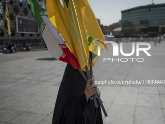 A veiled Iranian woman carries an Iranian flag and flags of Lebanon's Hezbollah before a gathering marking the memory of Hezbollah Secretary...