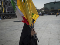 A veiled Iranian woman carries an Iranian flag and flags of Lebanon's Hezbollah before a gathering marking the memory of Hezbollah Secretary...