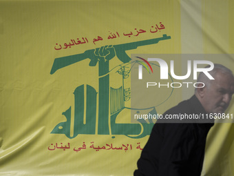 An elderly Iranian man stands in front of a flag of Lebanon's Hezbollah during a gathering marking the memory of Hezbollah Secretary General...