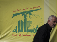 An elderly Iranian man stands in front of a flag of Lebanon's Hezbollah during a gathering marking the memory of Hezbollah Secretary General...