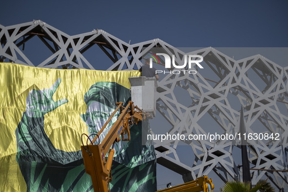 An Iranian worker hangs a banner featuring a portrait of Lebanon's Hezbollah Secretary General Hassan Nasrallah in Tehran, Iran, on October...