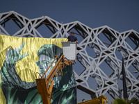 An Iranian worker hangs a banner featuring a portrait of Lebanon's Hezbollah Secretary General Hassan Nasrallah in Tehran, Iran, on October...