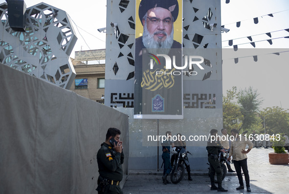 Iranian police officers stand under a banner featuring a portrait of Lebanon's Hezbollah Secretary General Hassan Nasrallah in Tehran, Iran,...