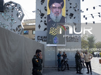 Iranian police officers stand under a banner featuring a portrait of Lebanon's Hezbollah Secretary General Hassan Nasrallah in Tehran, Iran,...