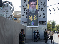 Iranian police officers stand under a banner featuring a portrait of Lebanon's Hezbollah Secretary General Hassan Nasrallah in Tehran, Iran,...