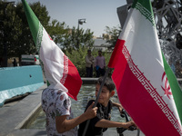 Two young Iranian boys hold Iranian flags while taking part in a gathering marking the memory of Lebanon's Hezbollah Secretary General Hassa...