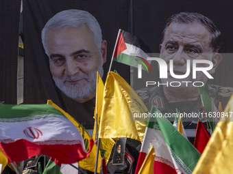 Iranian people wave a Palestinian flag, an Iranian flag, and flags of Lebanon's Hezbollah in front of portraits of the former commander of t...