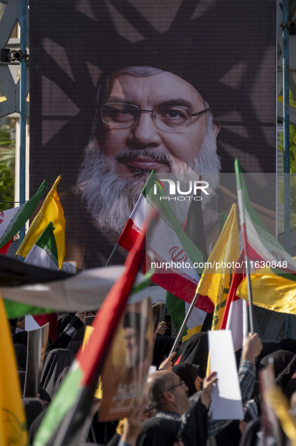 Iranian people wave flags in front of a portrait of Lebanon's Hezbollah Secretary General Hassan Nasrallah during a gathering marking the me...