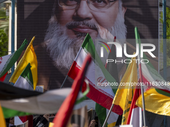 Iranian people wave flags in front of a portrait of Lebanon's Hezbollah Secretary General Hassan Nasrallah during a gathering marking the me...