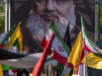 Iranian people wave flags in front of a portrait of Lebanon's Hezbollah Secretary General Hassan Nasrallah during a gathering marking the me...