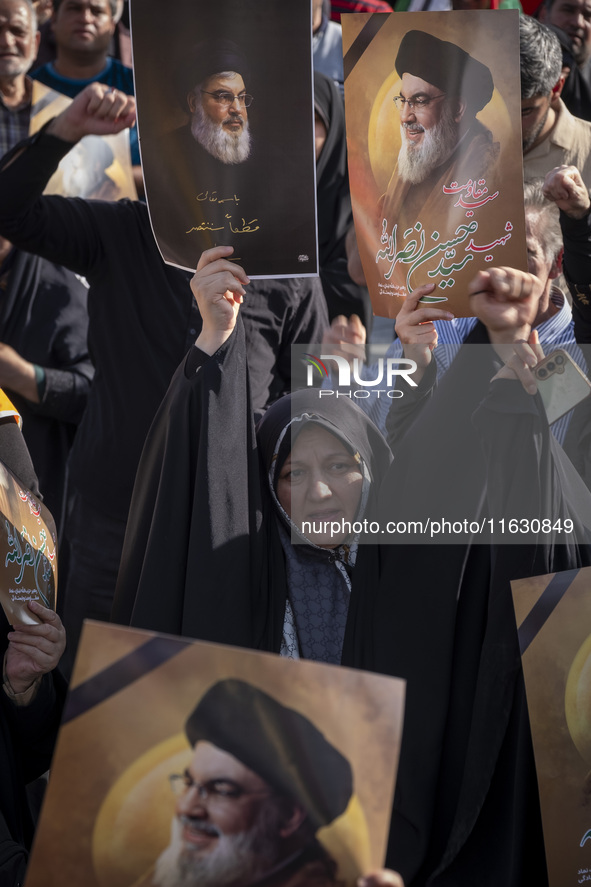 A veiled Iranian woman holds a portrait of Lebanon's Hezbollah Secretary General Hassan Nasrallah while shouting anti-Israeli slogans during...