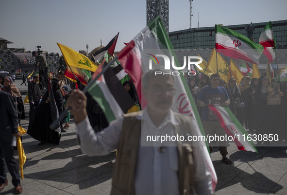 Iranian people wave Iranian flags and Lebanon's Hezbollah flags during a gathering marking the memory of Hezbollah Leader Hassan Nasrallah a...