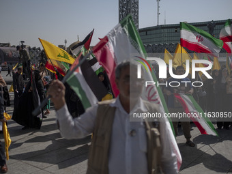 Iranian people wave Iranian flags and Lebanon's Hezbollah flags during a gathering marking the memory of Hezbollah Leader Hassan Nasrallah a...