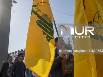 An Iranian man holds a flag of Lebanon's Hezbollah and a portrait of Hezbollah Secretary General Hassan Nasrallah during a gathering marking...