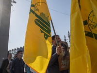 An Iranian man holds a flag of Lebanon's Hezbollah and a portrait of Hezbollah Secretary General Hassan Nasrallah during a gathering marking...