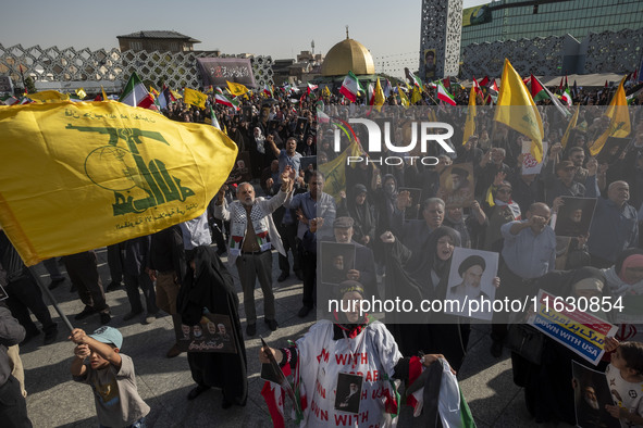 Iranian people hold flags of Lebanon's Hezbollah and portraits of Hezbollah Secretary General Hassan Nasrallah while taking part in a gather...