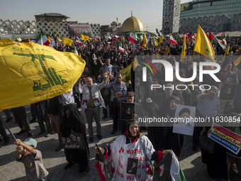 Iranian people hold flags of Lebanon's Hezbollah and portraits of Hezbollah Secretary General Hassan Nasrallah while taking part in a gather...