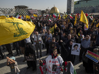 Iranian people hold flags of Lebanon's Hezbollah and portraits of Hezbollah Secretary General Hassan Nasrallah while taking part in a gather...