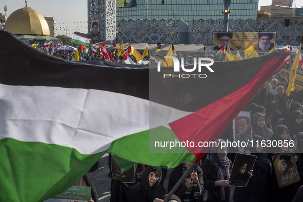 An Iranian man (not pictured) waves a Palestinian flag as others hold portraits of Lebanon's Hezbollah Secretary General Hassan Nasrallah an...