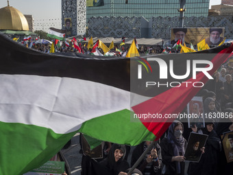 An Iranian man (not pictured) waves a Palestinian flag as others hold portraits of Lebanon's Hezbollah Secretary General Hassan Nasrallah an...