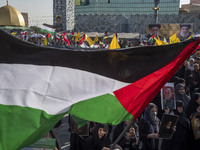 An Iranian man (not pictured) waves a Palestinian flag as others hold portraits of Lebanon's Hezbollah Secretary General Hassan Nasrallah an...