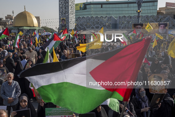 An Iranian man (not pictured) waves a Palestinian flag as others hold portraits of Lebanon's Hezbollah Secretary General Hassan Nasrallah du...