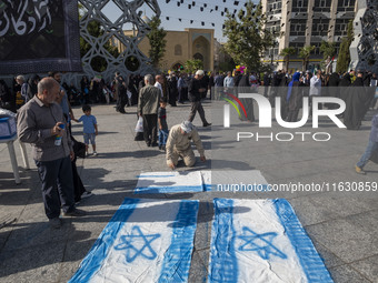 An Iranian man prepares Israeli flags to be set on fire during a gathering marking the memory of Lebanon's Hezbollah Secretary General Hassa...