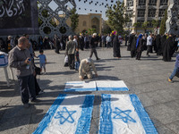 An Iranian man prepares Israeli flags to be set on fire during a gathering marking the memory of Lebanon's Hezbollah Secretary General Hassa...